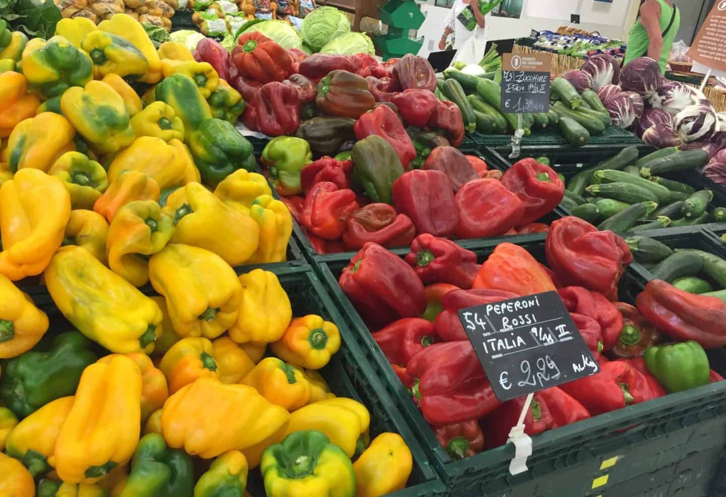 Lots of green, yellow and red Italian peppers in a supermarket.
